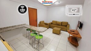 Un espacio habitable compacto con zona de cocina, sofá y televisor. Hay Wi-Fi disponible, y la habitación mide 42 pulgadas.