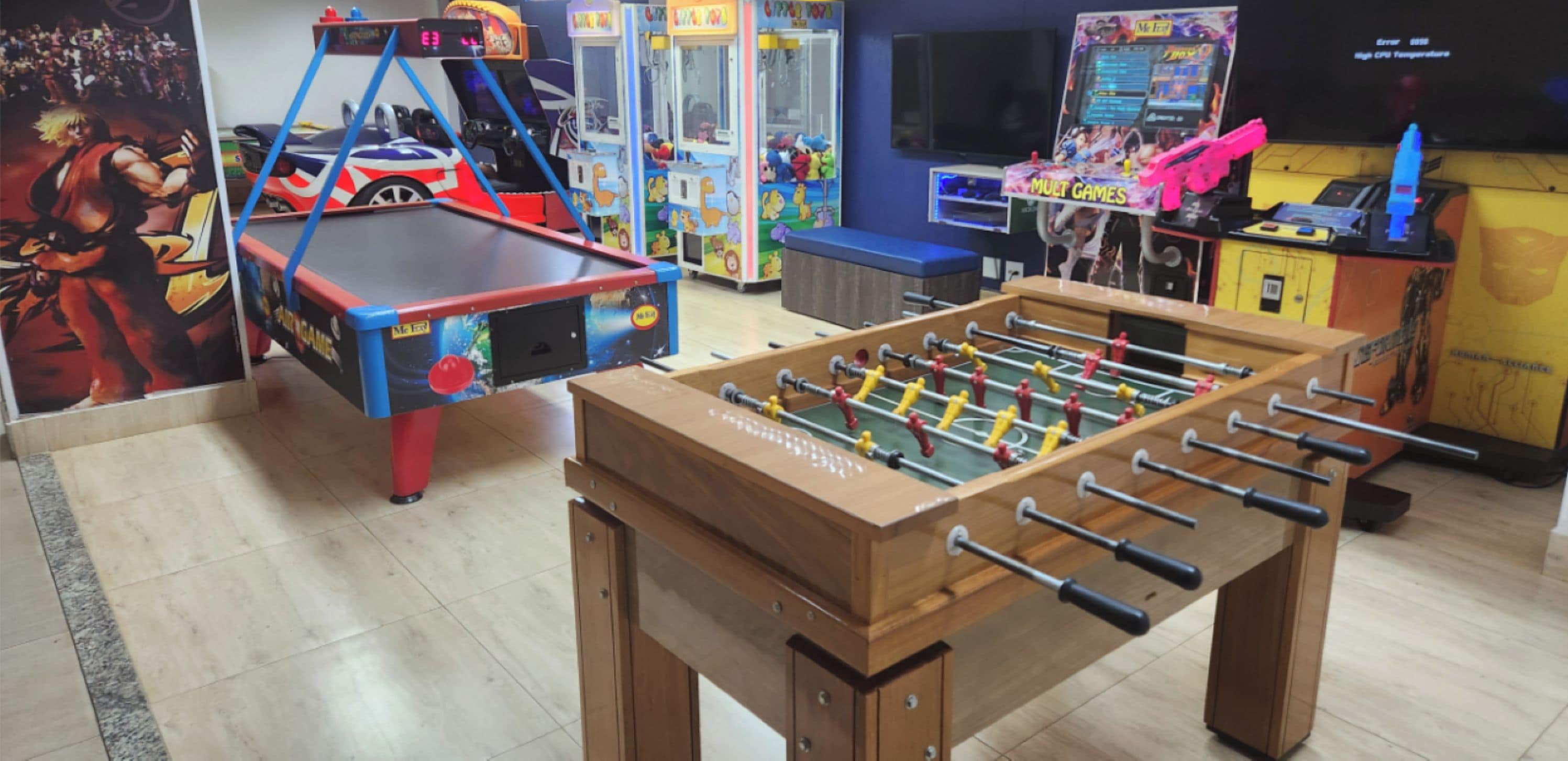 A room with a foosball table, a car-themed arcade machine, and a claw machine.
