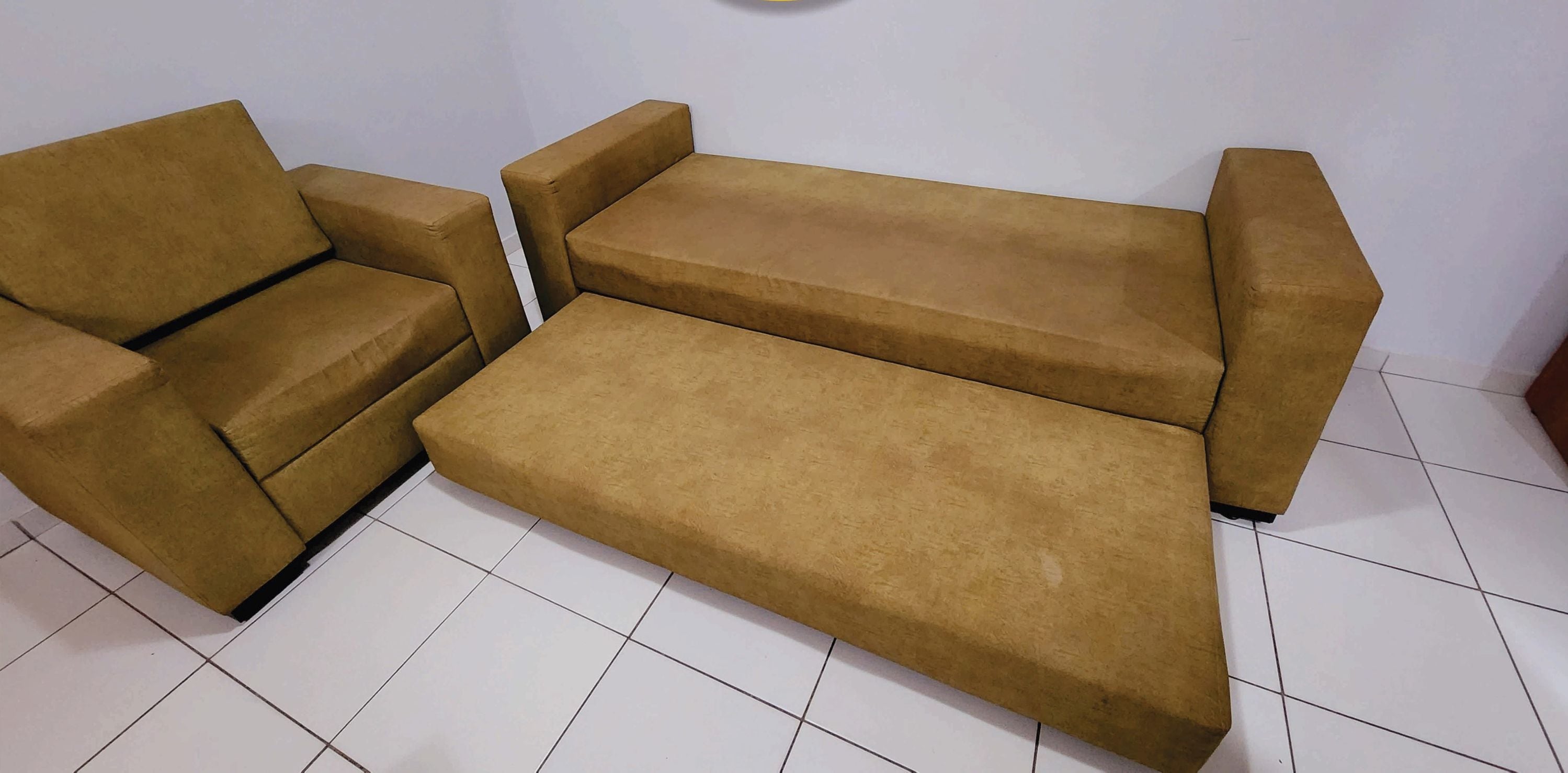 A sofa set in a room with white tiled flooring.