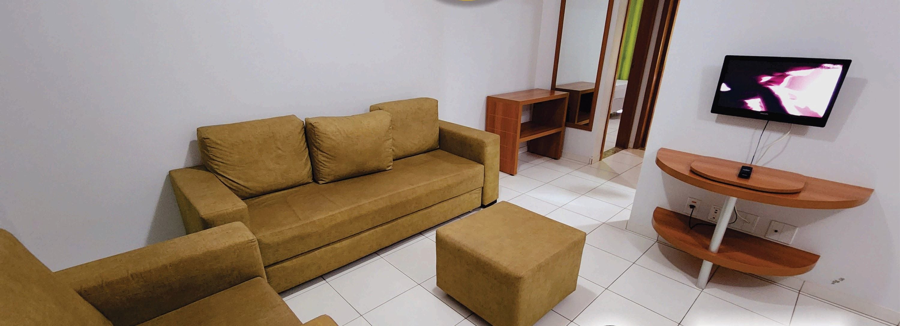 Ein Wohnzimmer mit Sofa, Hocker und Fernseher. Es gibt ein Schild mit der Aufschrift 'kostenloses WLAN' und ein 42-Zoll-Fernseher.