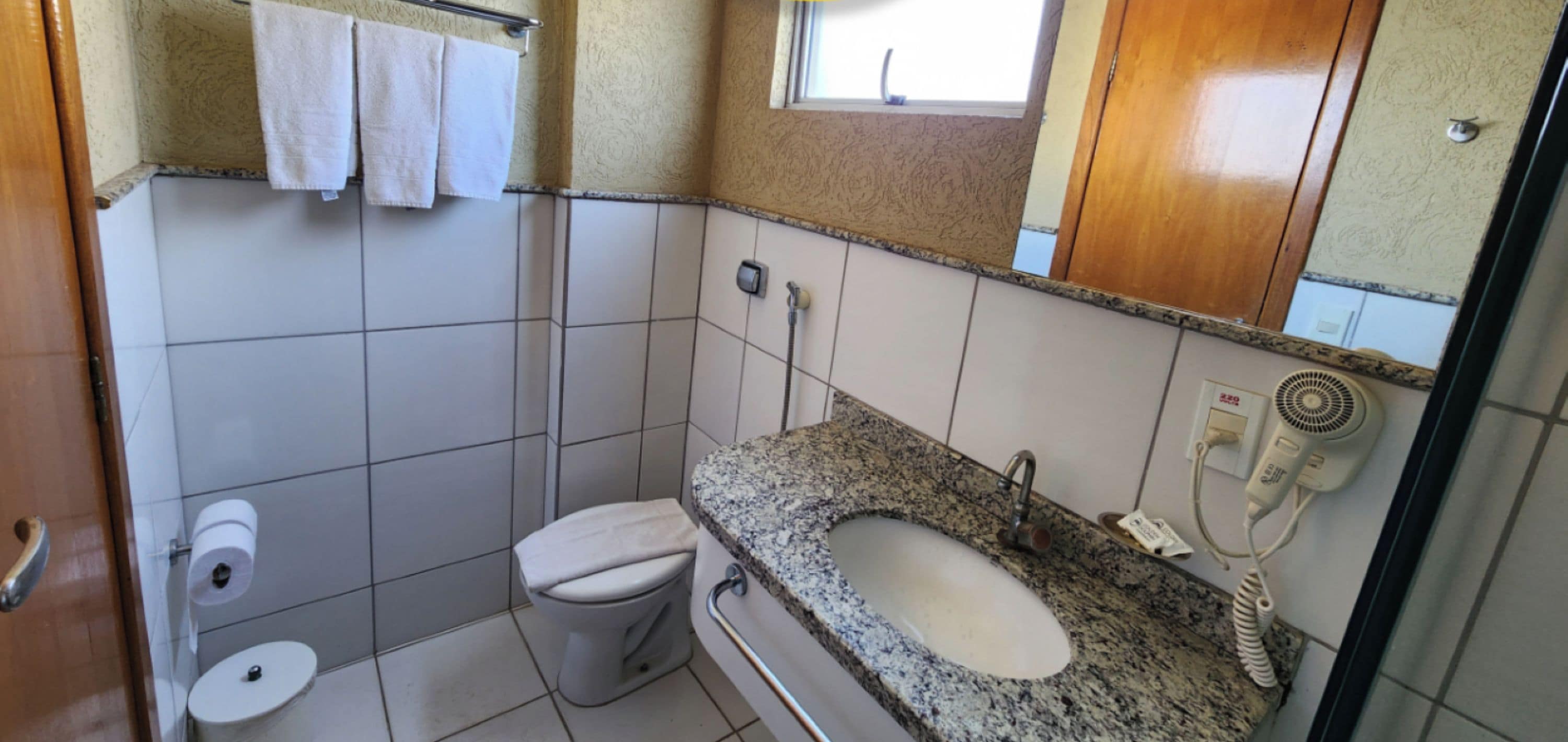 Un baño con inodoro, lavamanos y toallero.