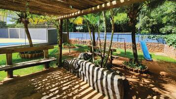 A covered outdoor area with a pool, wooden benches, and a playground.