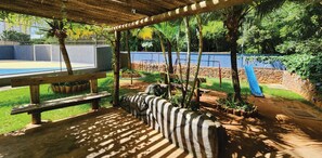 A covered outdoor area with a pool, wooden benches, and a playground. - Golden Dolphin GrandHotel - Piscinas 24h (Caldas Novas)