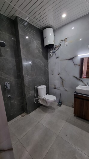 Enjoy a refreshing shower in this sleek bathroom with a handheld showerhead, pedestal sink, and handheld bidet.