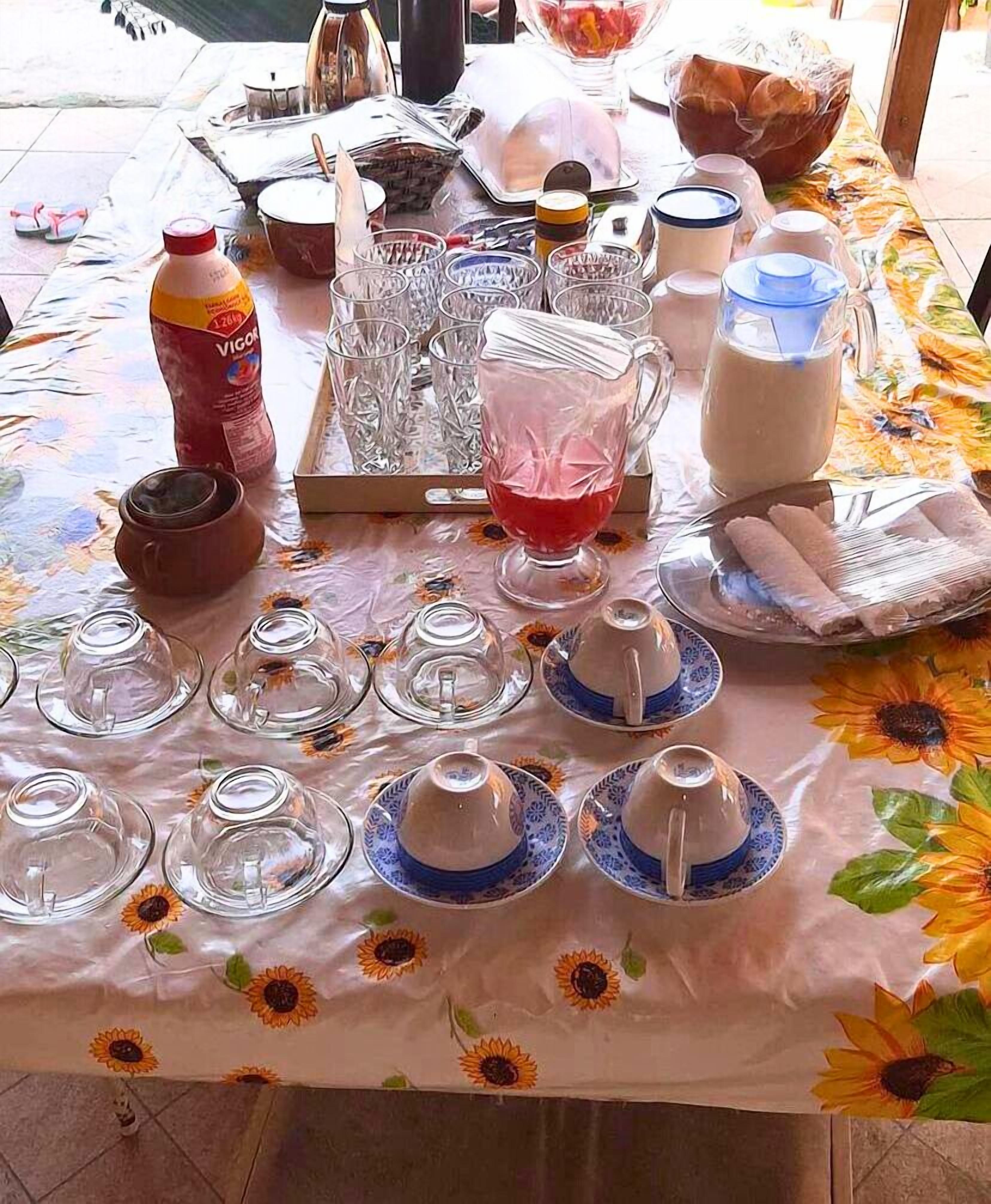 A table set with clear glassware, a pitcher, and a bottle, covered by a floral tablecloth.