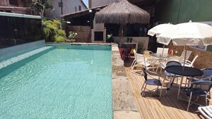 A clear swimming pool with lounge chairs and umbrellas. - Pousada Ilha Bonita (Guarujá)