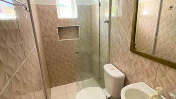 Baño con inodoro, lavamanos, ducha y pared con diseño.