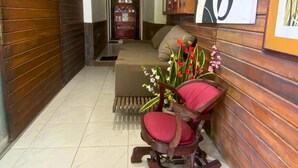 A hallway with a wooden wall, a rocking chair with red cushions, and a hanging light fixture. - Pousada Ilha Bonita (Guarujá)