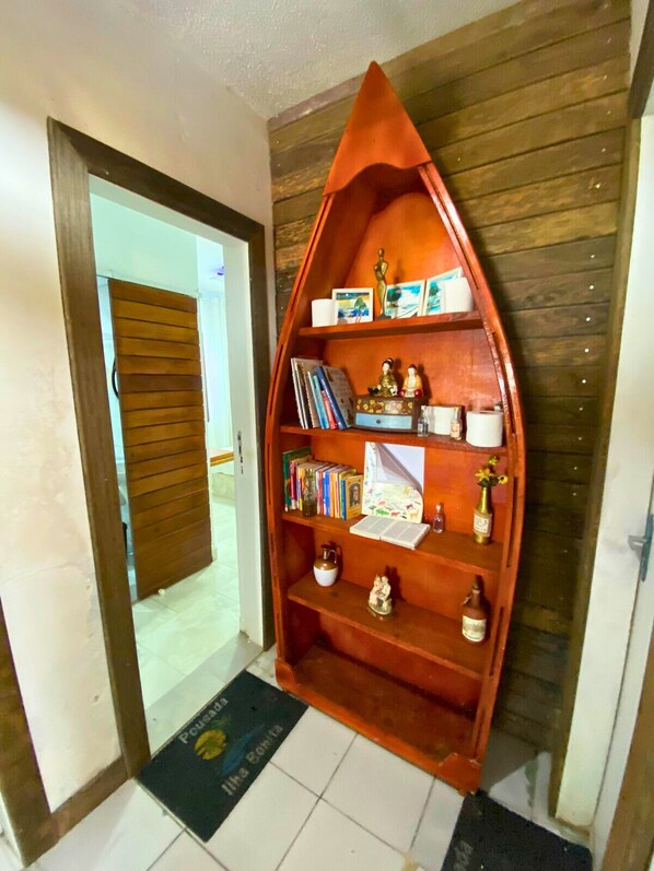Una estantería en forma de barco de madera en un pasillo con una puerta de madera y un felpudo negro en el suelo.