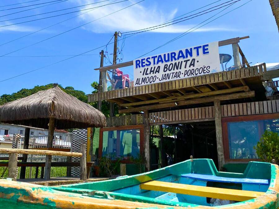 A restaurant with a signboard advertising 'ILHA BONITA' and 'ALMOÇO JANTAR PORCOES'.