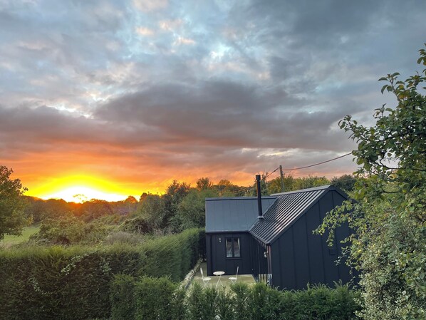 A modern house with a dark exterior, surrounded by lush greenery and a clear sky. - Beautiful re-imagined country chapel in peaceful hamlet (Otford)