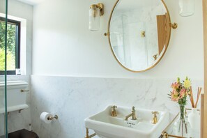 A bathroom with a white marble sink, gold fixtures, and a large mirror with a gold frame.