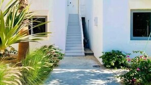 A white building with a staircase leading to a door, surrounded by greenery and a clear sky. - Rustic 1 BR-Apt@ Swanlake - El Gouna (Second Hurghada)