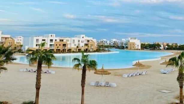A resort with a large swimming pool, palm trees, and beach chairs. - Rustic 1 BR-Apt@ Swanlake - El Gouna (Second Hurghada)