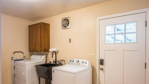 A laundry room with a washer, dryer, and a wooden cabinet.