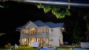 Ein zweistöckiges Haus mit Swimmingpool und überdachter Terrasse.