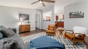 A living room with a ceiling fan, a sofa, a coffee table, and a dining area with chairs.