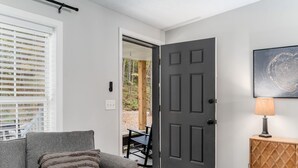 A modern living room with a grey sofa, a wooden cabinet, and a door leading to an outdoor area.