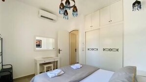 A bedroom with a bed, a bedside table, a mirror, and a wardrobe.