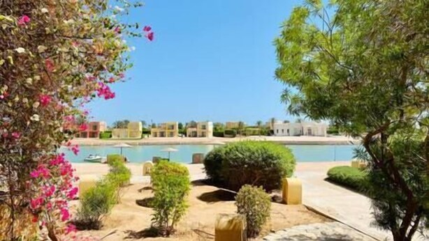 A resort with a pool, greenery, and buildings in the background.