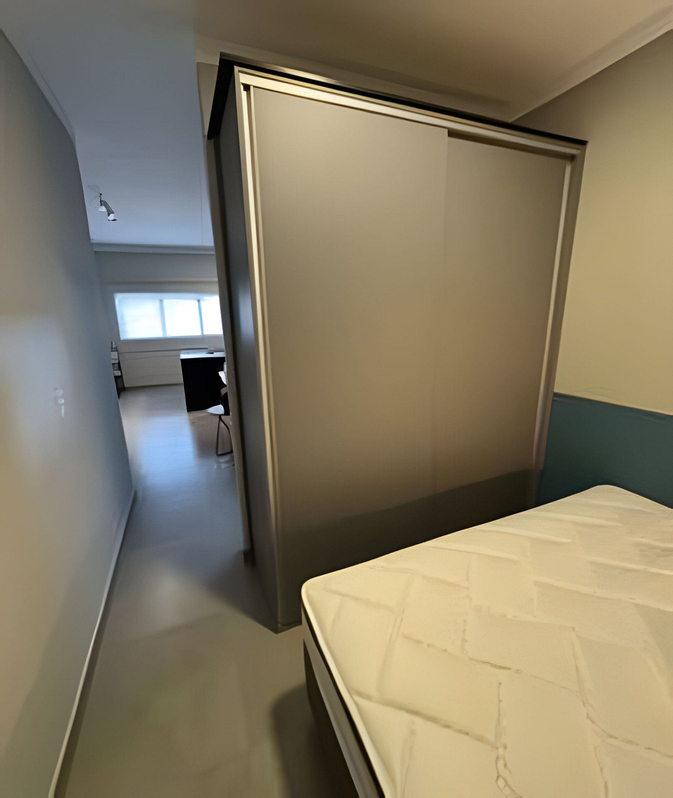 Quarto com cama, guarda-roupa e escrivaninha com cadeira.