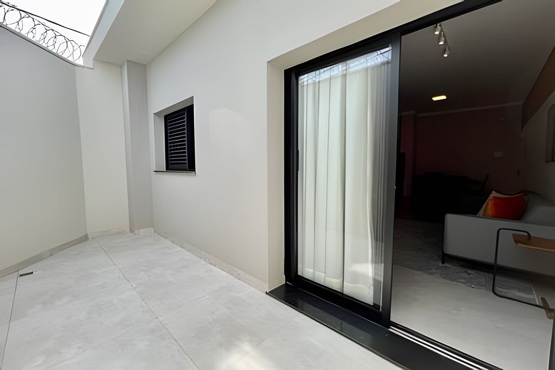 Um interior moderno com uma porta de correr de vidro que dá para uma sala de estar com sofá e mesa de centro.