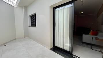 Um interior moderno com uma porta de correr de vidro que dá para uma sala de estar com sofá e mesa de centro.