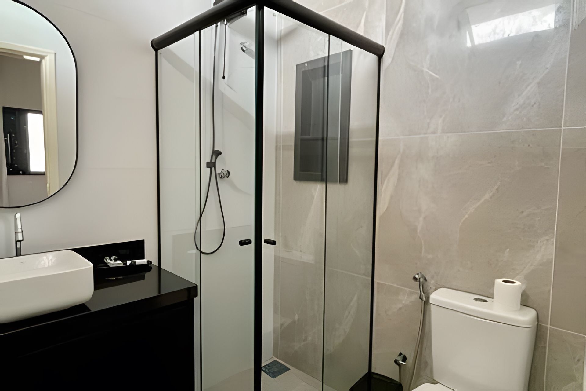 A modern bathroom with a glass-enclosed shower, a white sink, and a toilet.