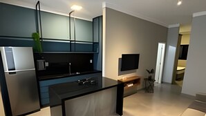 Een moderne keuken met een ingebouwde oven, een eethoek met een houten tafel en een grijze bank.
