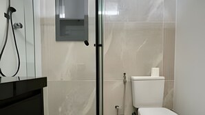 Moderni kylpyhuone, jossa on wc, bidee ja lasinen suihkuseinä.