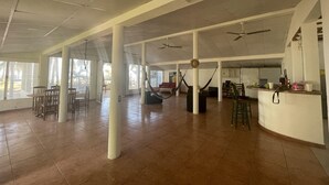 A spacious indoor area with high ceilings, large windows, and a central seating area with chairs and tables. - Sugarloaf Beachhouse and Surf Lodge (Jucuaran)