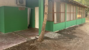 A green building with a tiled entrance, a tree in front, and a window with curtains. - Sugarloaf Beachhouse and Surf Lodge (Jucuaran)