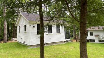 Escape to a secluded cabin surrounded by mature trees and a well-maintained lawn.