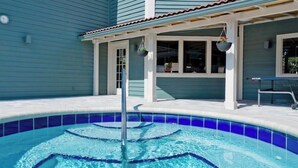 Une piscine dont le centre est d’un bleu limpide, entourée d’un patio couvert avec un banc.
