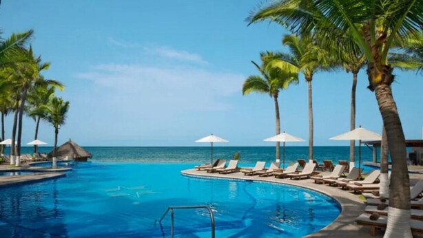A pool with lounge chairs and umbrellas, surrounded by palm trees and a view of the ocean. - Fully renovated top floor oceanfront condo. (Bucerias)