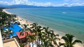 A beach resort with a swimming pool, palm trees, and a view of the ocean. - Fully renovated top floor oceanfront condo. (Bucerias)