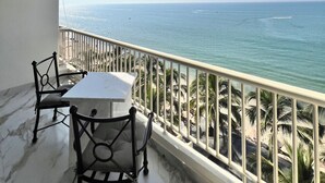 A balcony with a table and chairs, overlooking the sea with a clear view of the ocean and a parachute in the distance. - Fully renovated top floor oceanfront condo. (Bucerias)