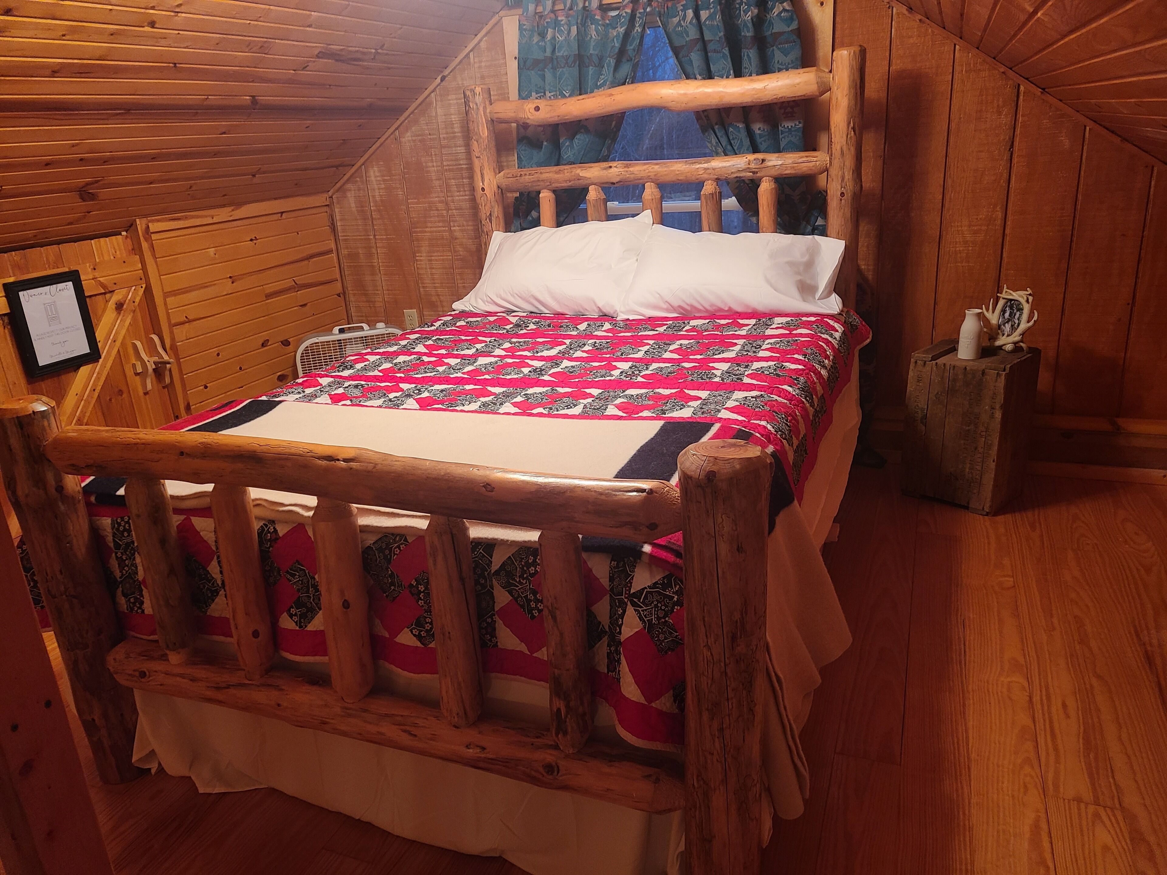 A wooden bed with a quilt in a cabin-style room.