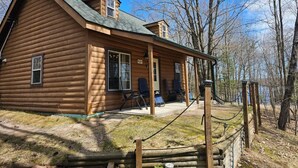 A log cabin with a porch, two chairs, and a small deck area. - Cozy Hayward Moose Lake Getaway (Hayward)