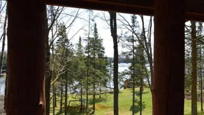 A view from inside a cabin with a wooden structure, overlooking a lake surrounded by trees. - Cozy Hayward Moose Lake Getaway (Hayward)