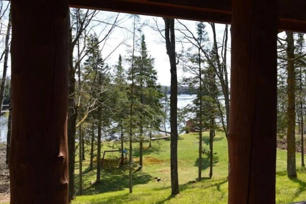 A view from inside a cabin with a wooden structure, overlooking a lake surrounded by trees. - Cozy Hayward Moose Lake Getaway (Hayward)