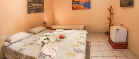 Una cama individual con ropa de cama floral, una mesita de noche pequeña y un radiador de pared.