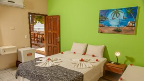 Ein Hotelzimmer mit Bett, Nachttisch, Schreibtisch und einem Bild von einer Strandansicht.