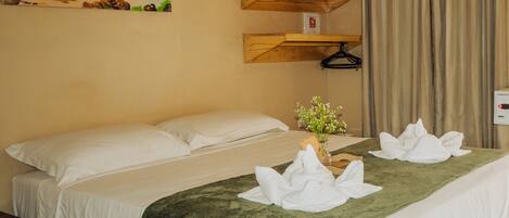 Una camera d'hotel con un letto, un quadro raffigurante una spiaggia, una mensola in legno e una tenda.