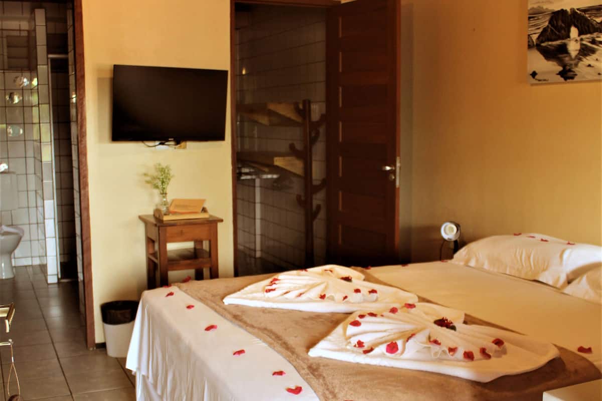 Une chambre d’hôtel équipée d’un lit, d’un téléviseur fixé au mur et d’un espace douche.