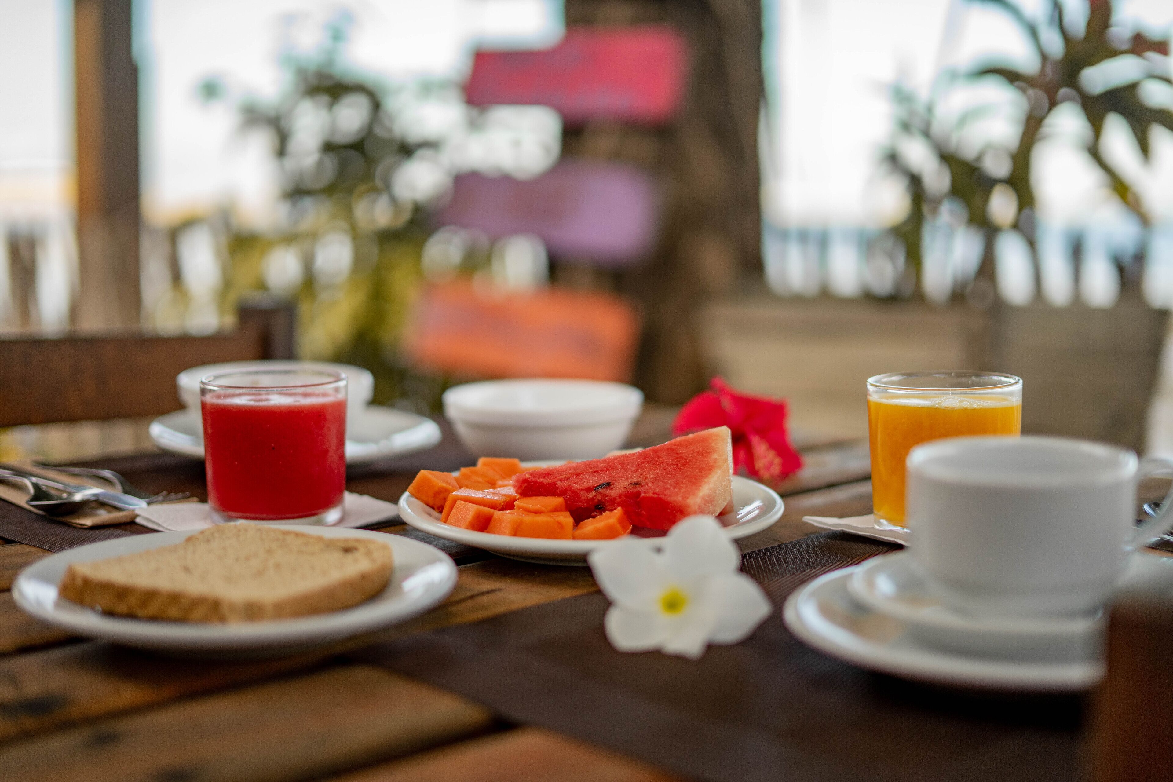 A breakfast table with a plate of toast, watermelon, and orange juice.