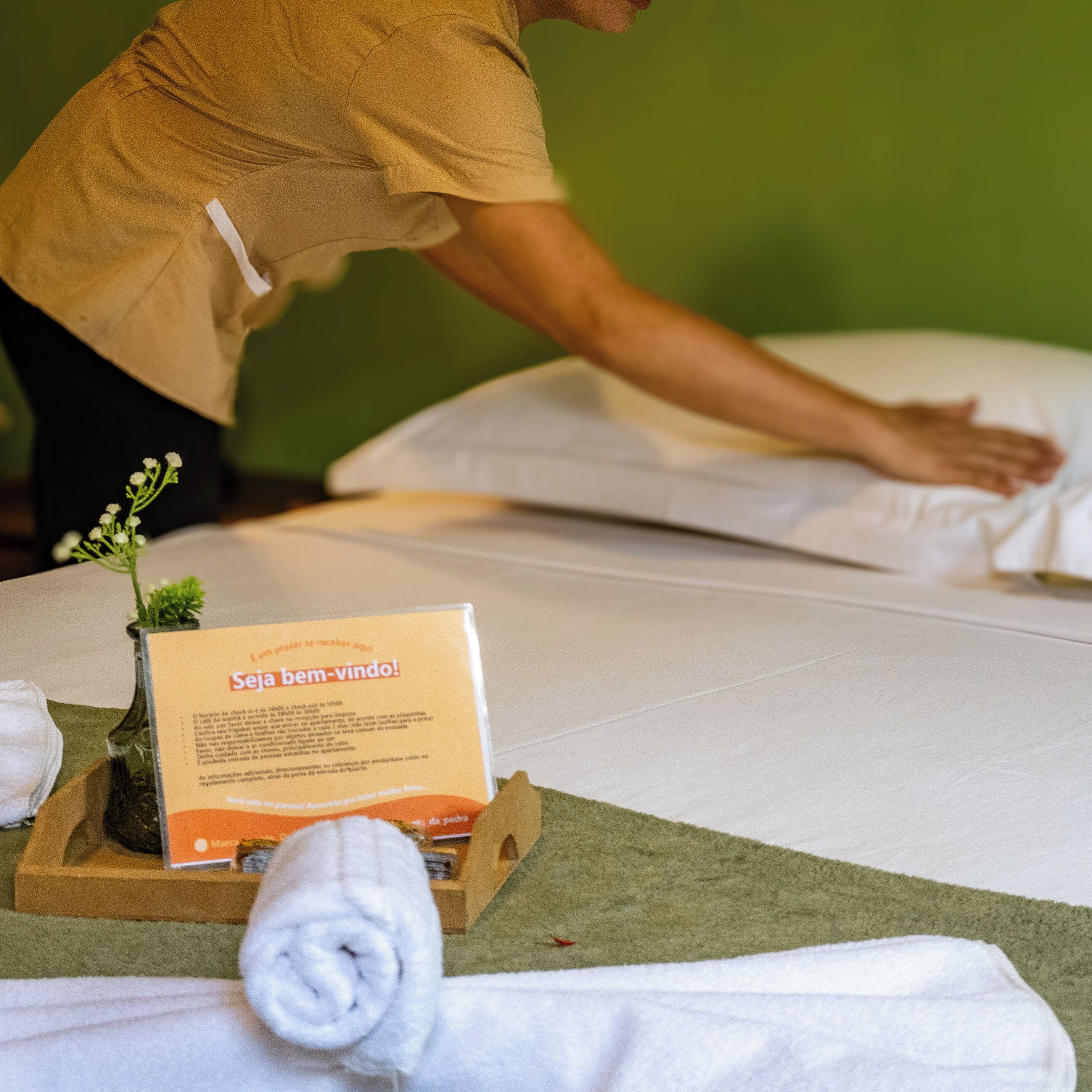 A person attending to a bed with a message card on it.