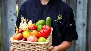 Una persona sostiene una cesta de mimbre llena de diversos vegetales.