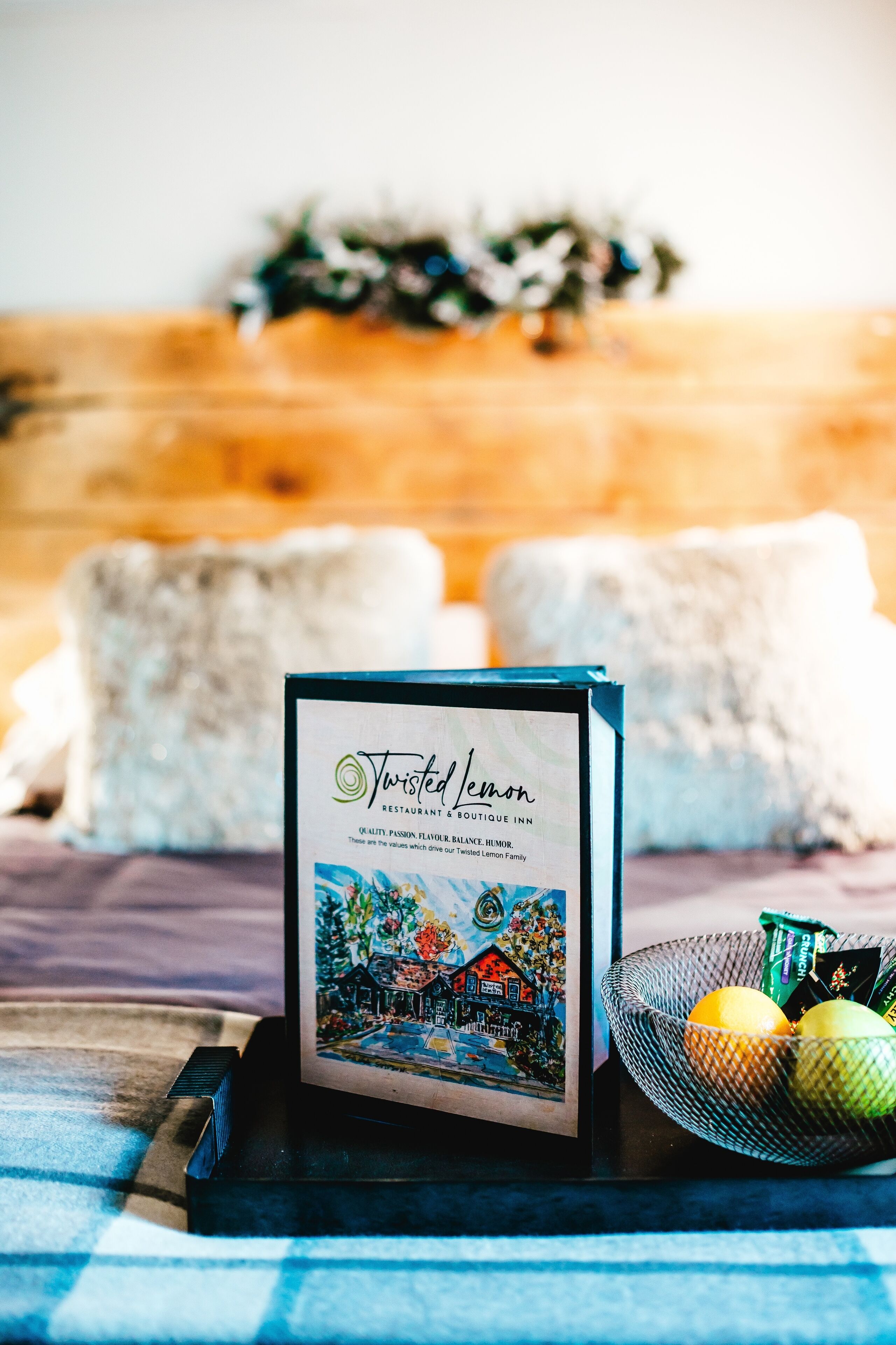 Un menu incorniciato del ristorante e boutique hotel Twisted Lemon, con un cesto di limoni e una candela su un tavolo.
