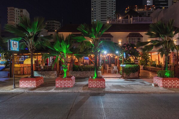 A hotel entrance with palm trees, brick planters, and a sign with a 'H' symbol. - HOTEL BALUARTE BOUTIQUE CARTAGENA  (Cartagena)